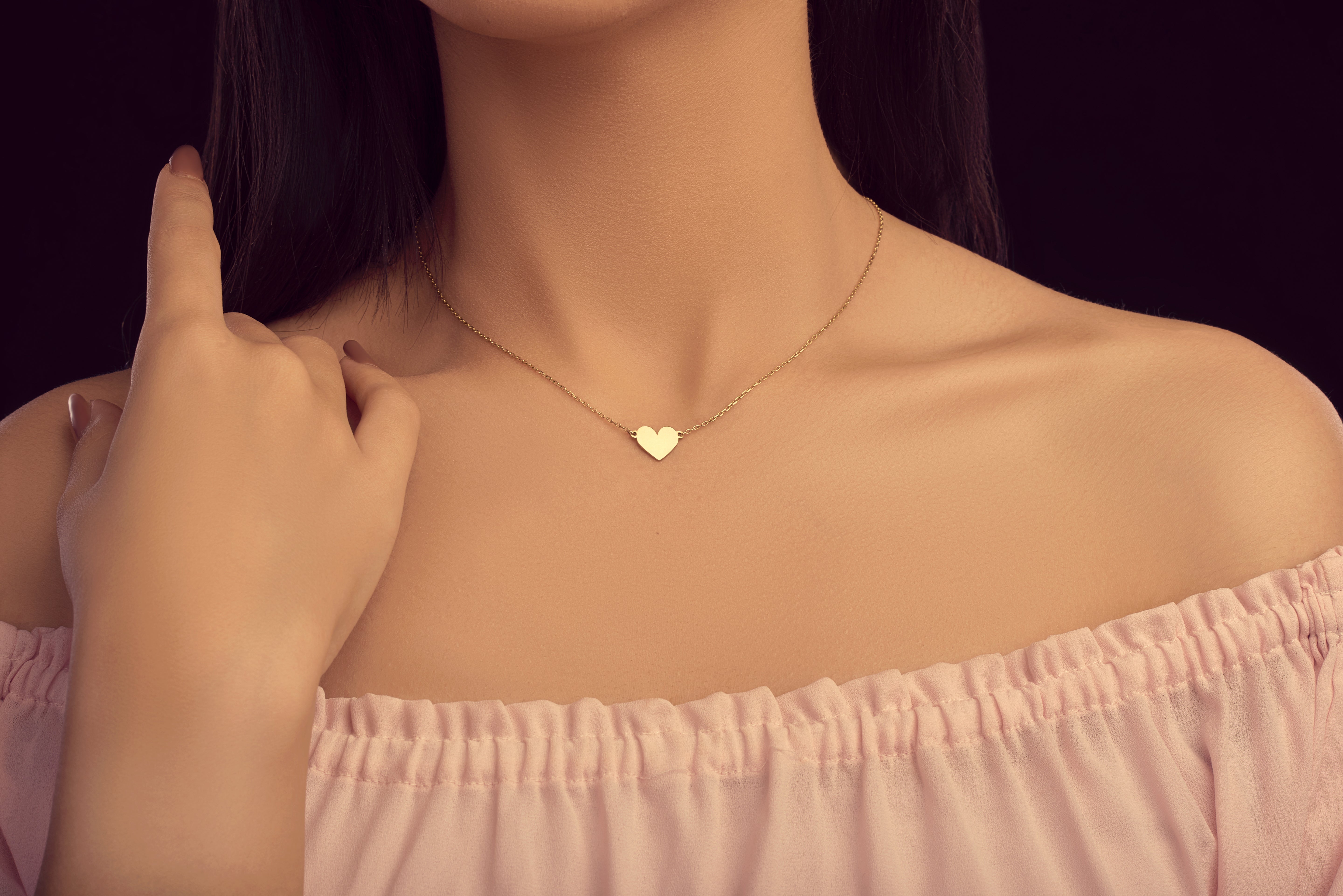 Heart-shaped necklace worn by a person with a blurred background