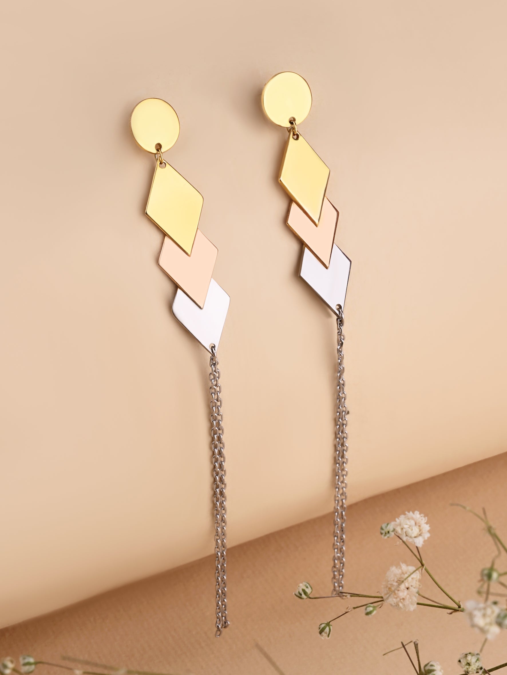 Gold and beige geometric earrings with chain details on a beige background