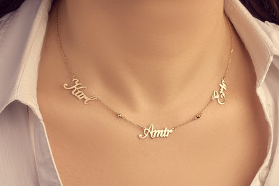 Gold necklace with name pendants on a person wearing a white shirt.
